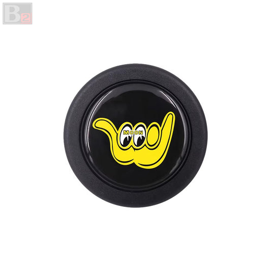 A black horn button with a yellow 'moon eyes' logo in the center.